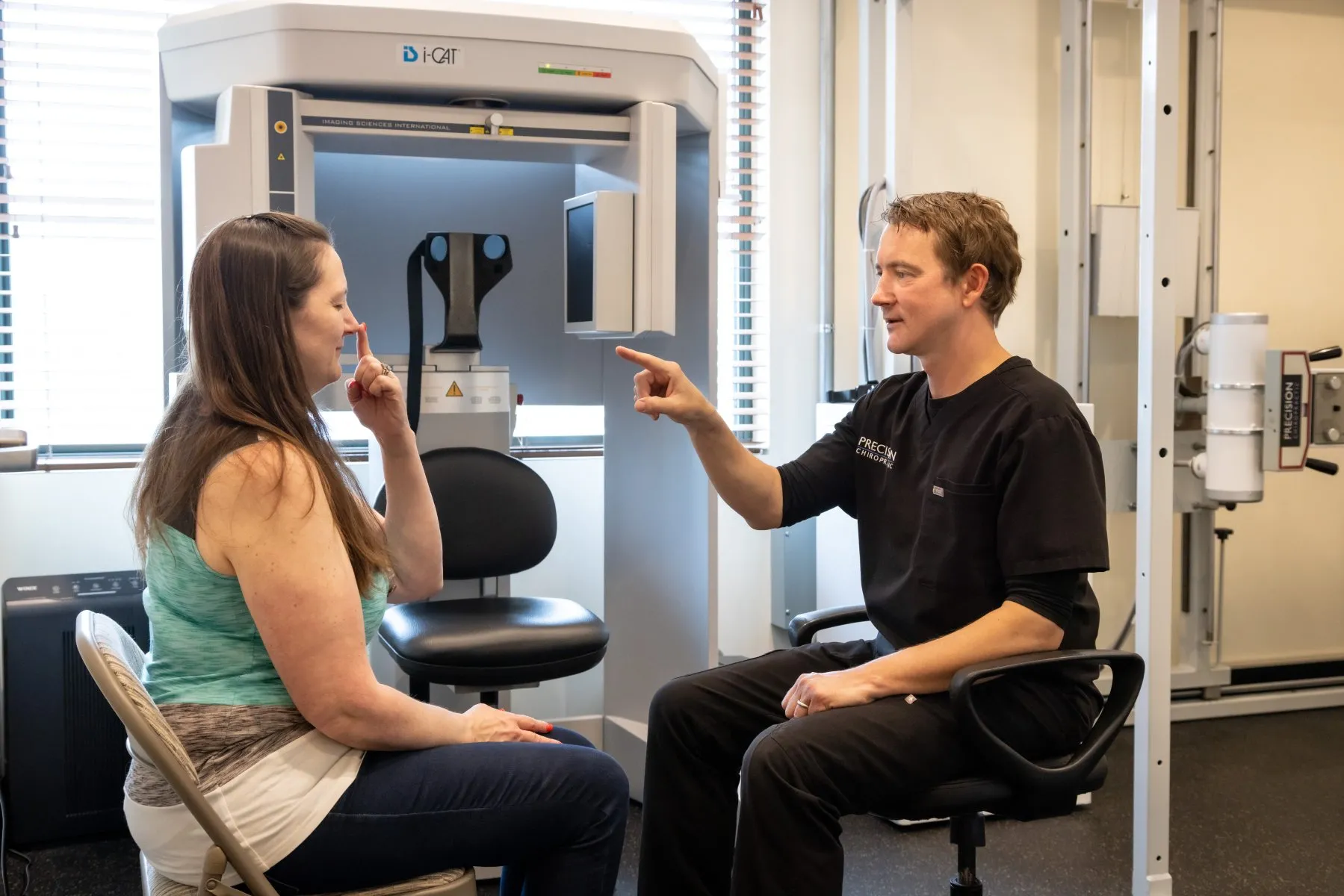 Chiropractor conducting a seated neurological assessment with a patient as part of a comprehensive NeuroStructural Exam at Precision Chiropractic in Vermont.